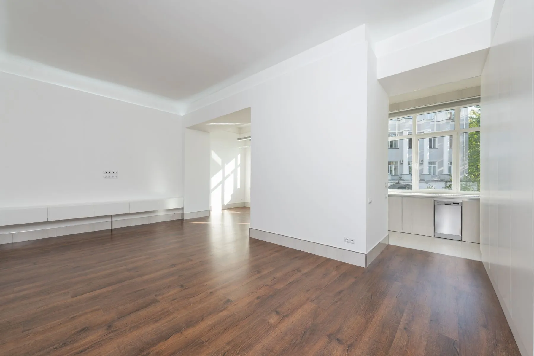 A bright empty Berlin living room with a wide window and wooden floor