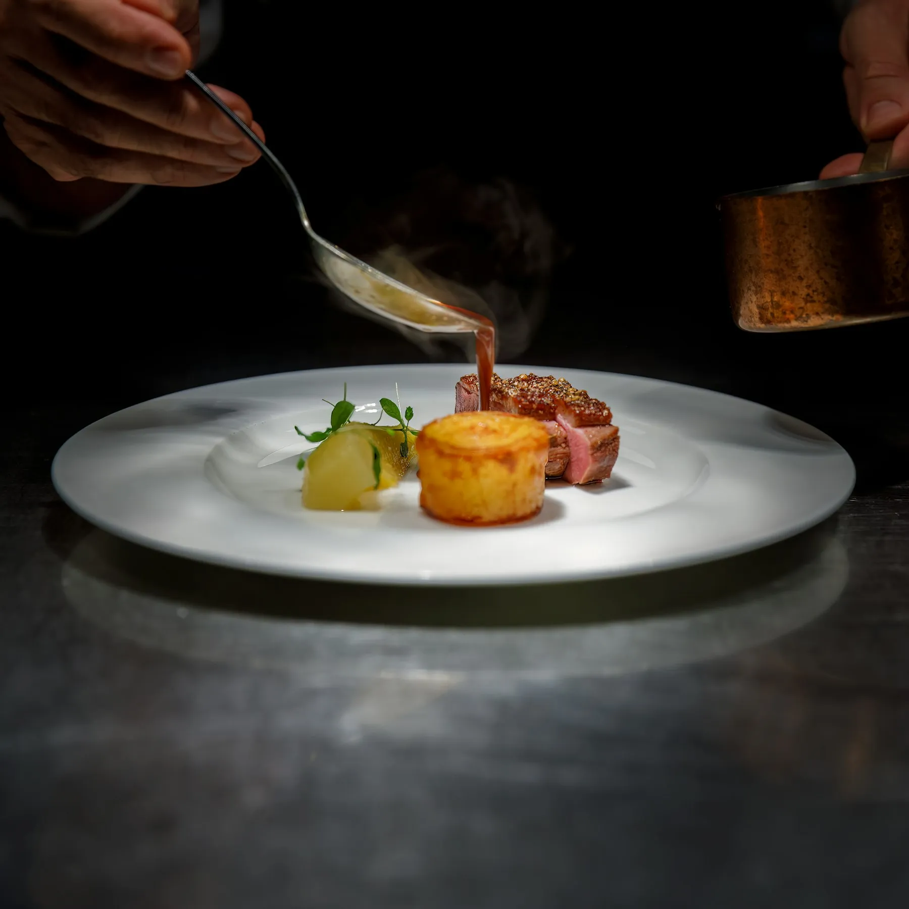 A chef plating a dish at the pass